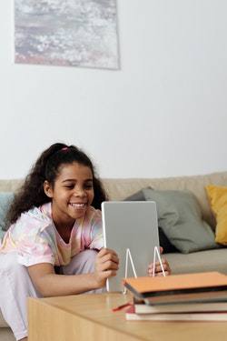 Photo of a girl smiling and looking at a tablet computer
